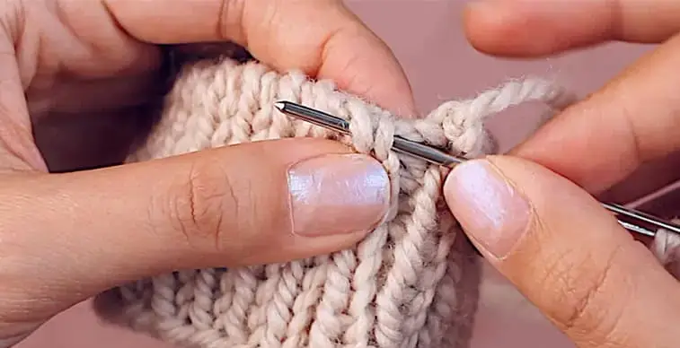 hands knitting a bind off in the round